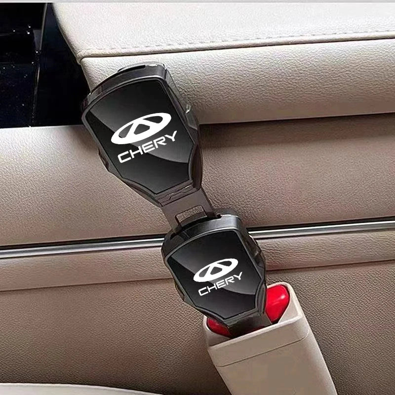 Two black car seatbelt release lockers with white CHERY logos, clipped onto a beige leather car seatbelt buckle.