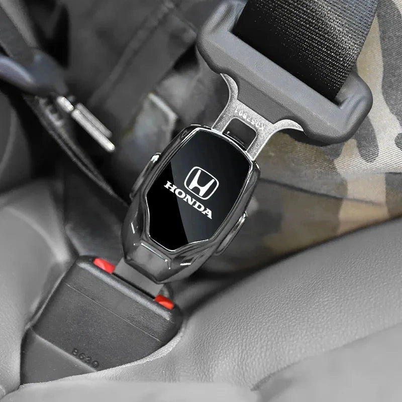 Honda logo metal seat belt clip extender inserted into seat belt buckle inside car interior