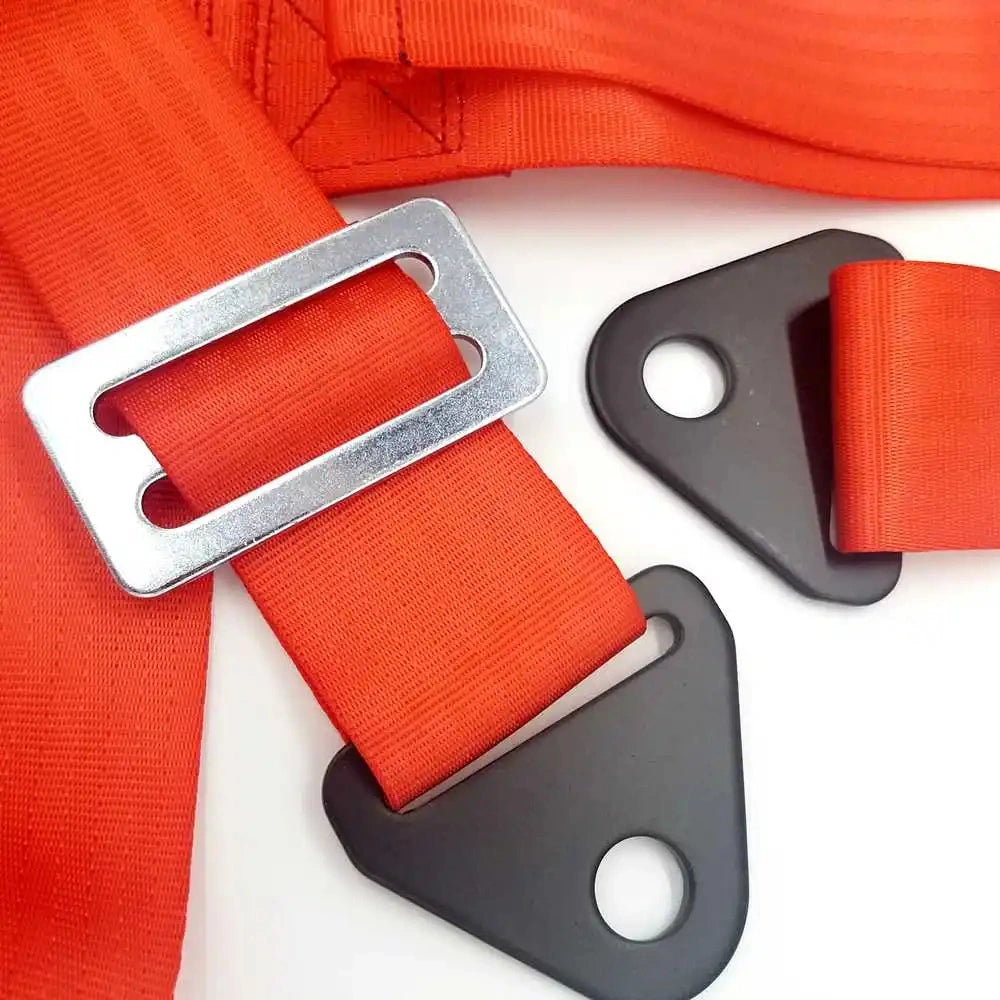 Close-up of red 4-point racing harness hardware showing heavy-duty steel mounting brackets and metal strap adjuster buckle.