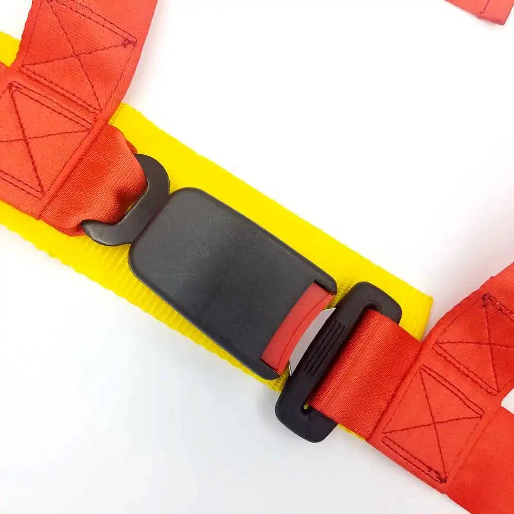 Close-up of a red 4-point racing harness showing the heavy-duty quick-release buckle, reinforced nylon stitching, and yellow protective sleeve.